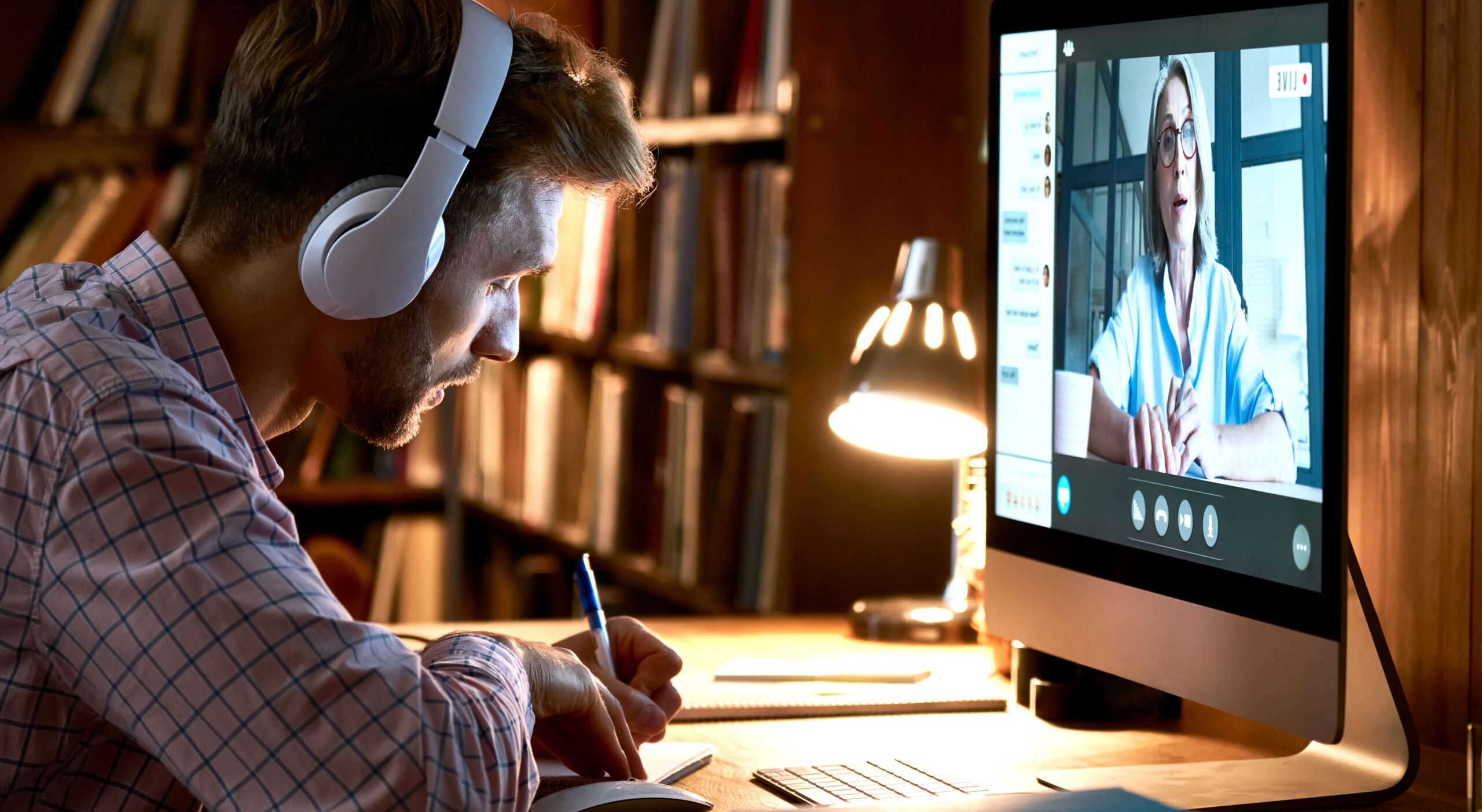 Male student wearing headphones video conference calling watching webinar.
